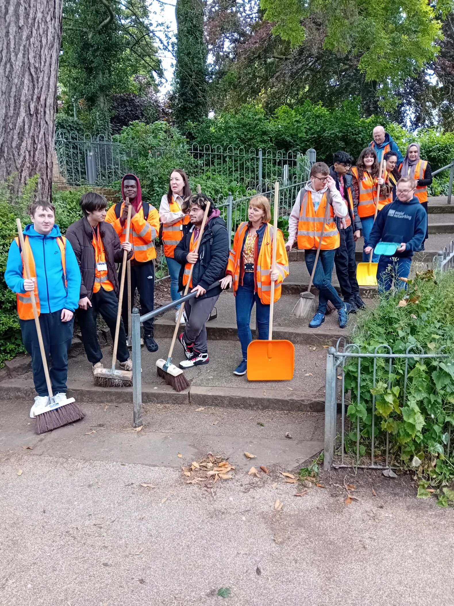 students in orange high vis vests standing on steps