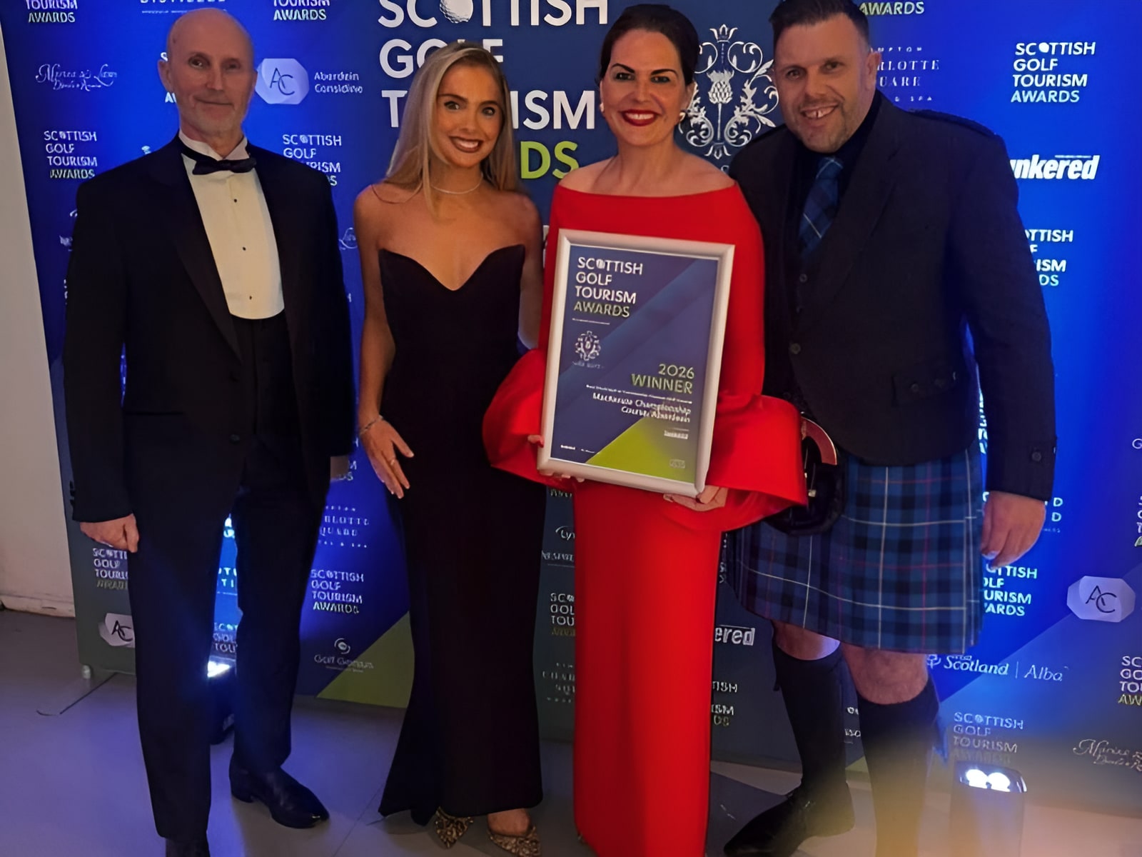 Four people posing with a Scottish Golf Tourism Awards 2026 Winner certificate at a formal awards ceremony.