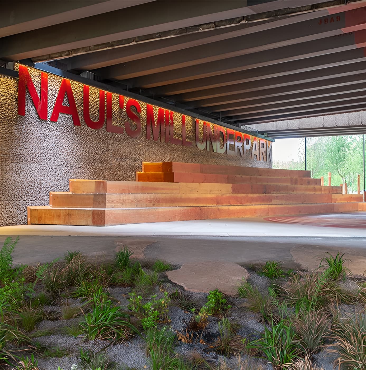 Nauls Mill Underpark seating area with timber steps, gabion wall, and red signage beneath a road bridge