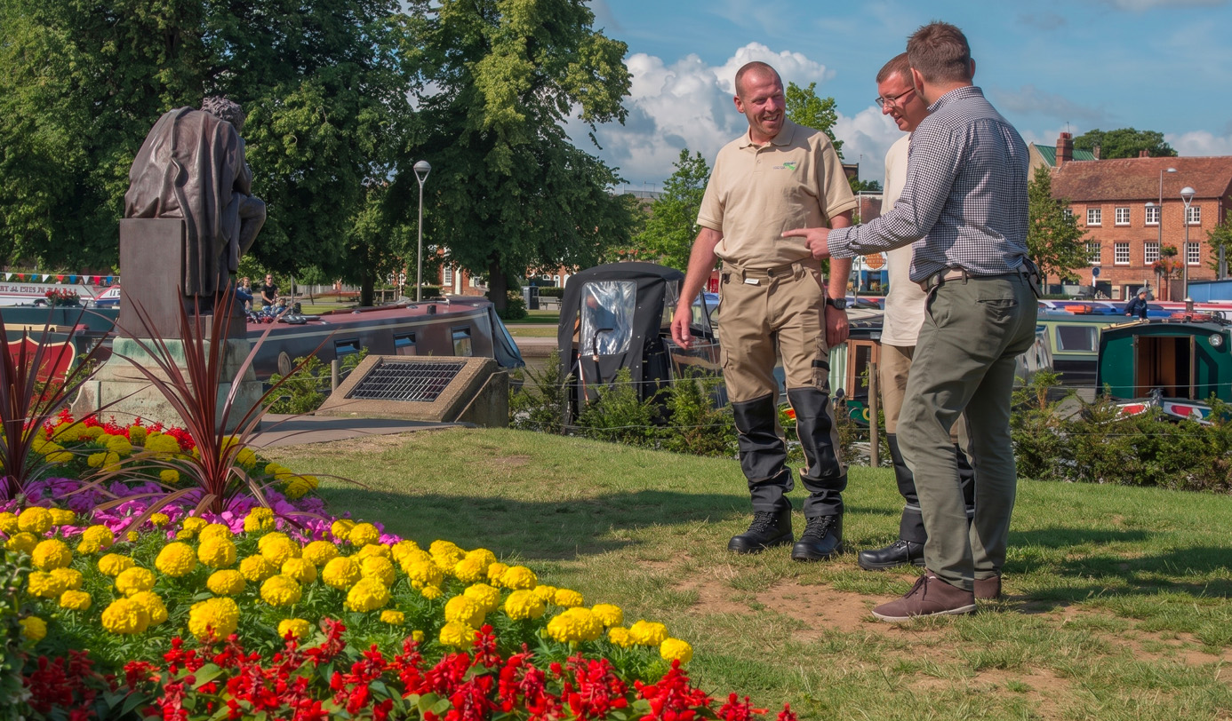 An idverde grounds manager and a client discussing a canalside planting scheme beside a colourful summer bedding display in Stratford-upon-Avon.