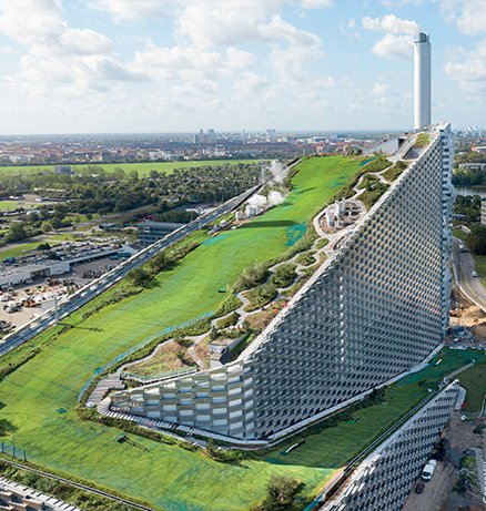 Aerial view of CopenHill waste-to-energy plant in Copenhagen with sloped green roof ski slope and walking paths
