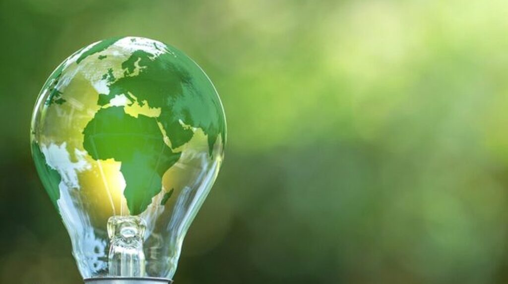 Green globe map inside a light bulb against a blurred green background