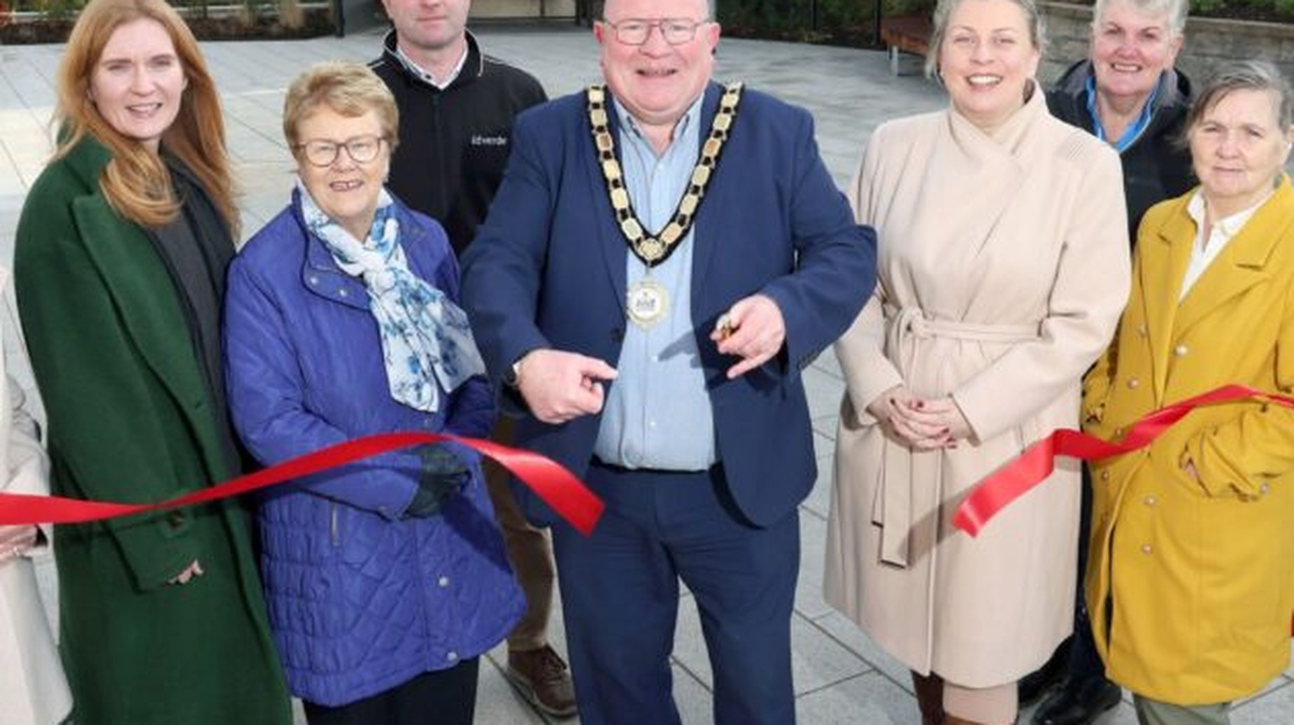 Chairperson cutting red ribbon at Doagh community space opening with attendees