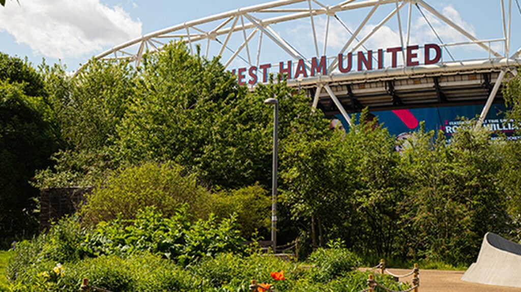 West Ham United stadium entrance surrounded by lush green trees and shrubs