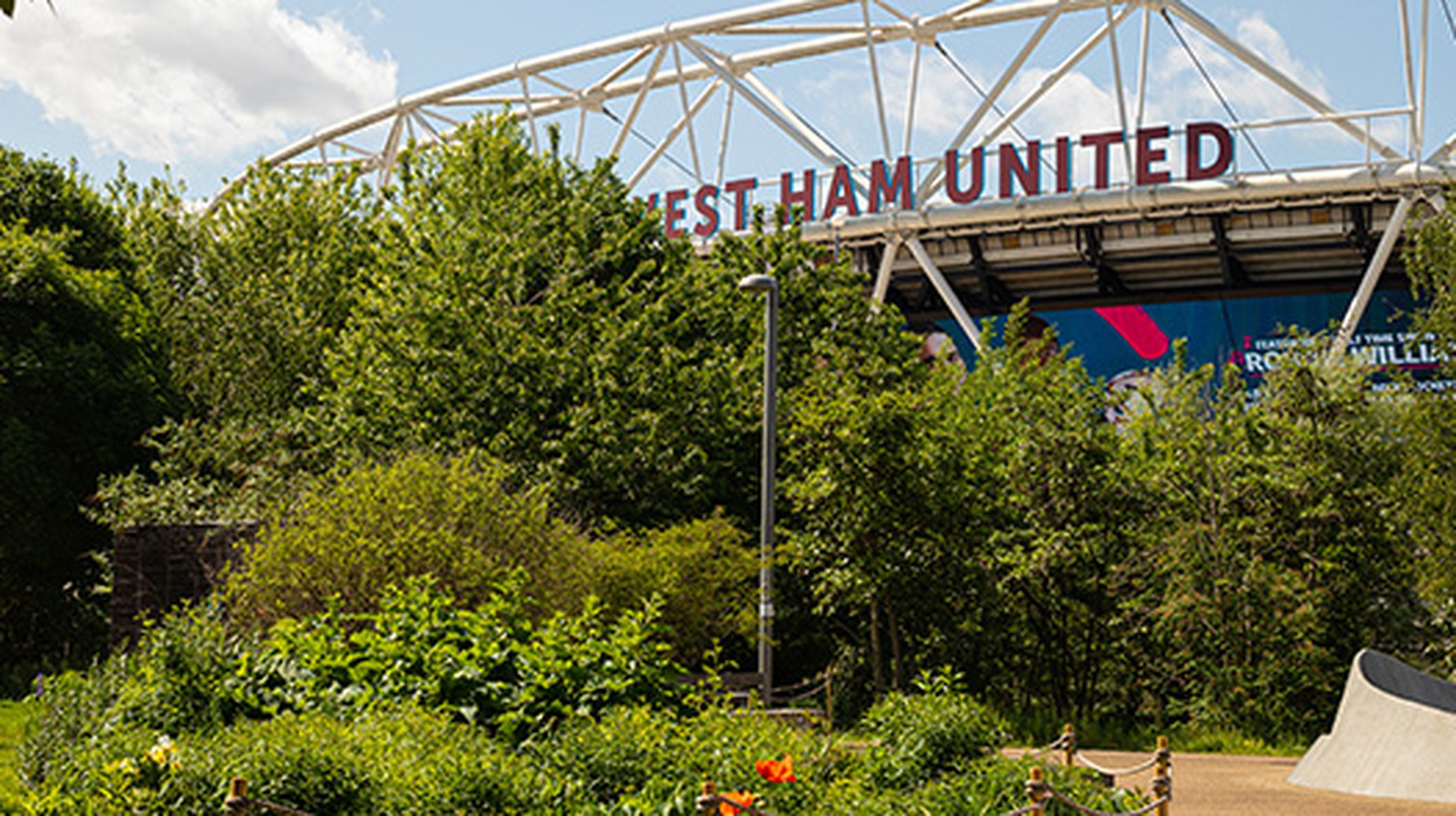 West Ham United stadium entrance surrounded by lush green trees and shrubs