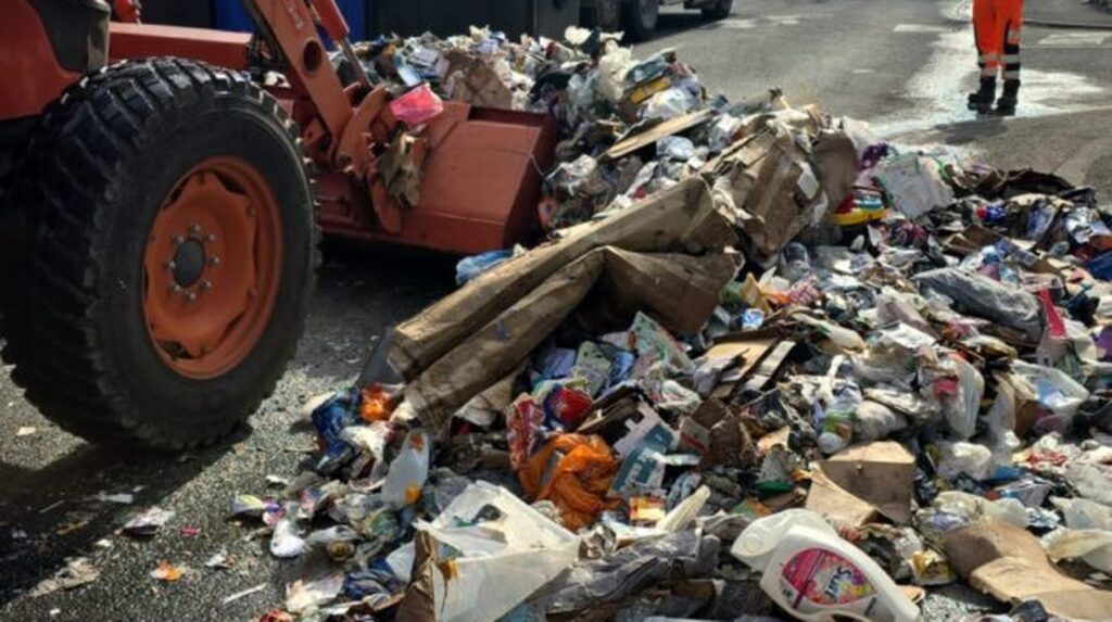 Loader clearing spilled waste from bin lorry fire on Trowbridge road
