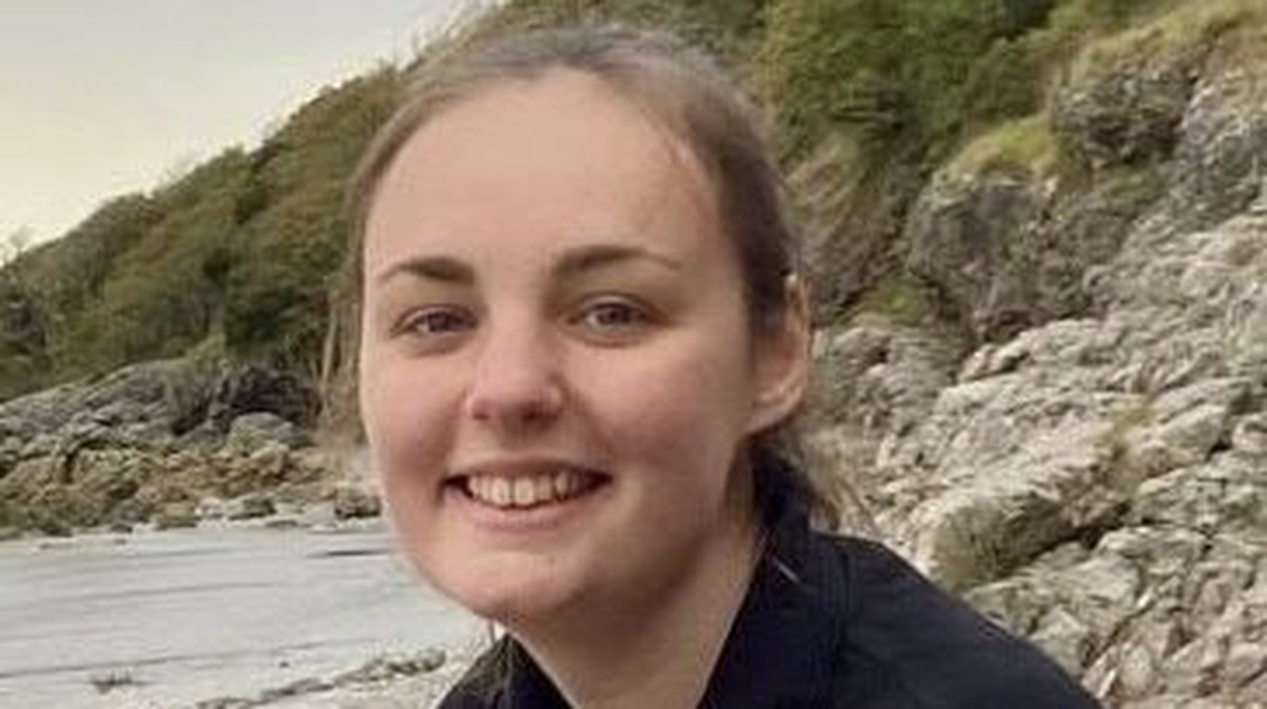 Smiling new Nature Engagement Officer standing near rocky riverside landscape in Barrow-in-Furness