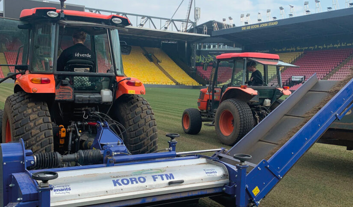 Two idverde operatives operating Kubota tractors fitted with a Koro FTM field topper machine on the pitch at Vicarage Road stadium